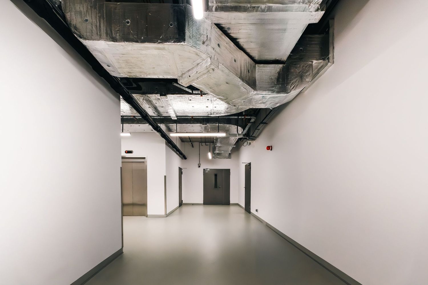 A service corridor with ductwork and cable tray in the ceiling