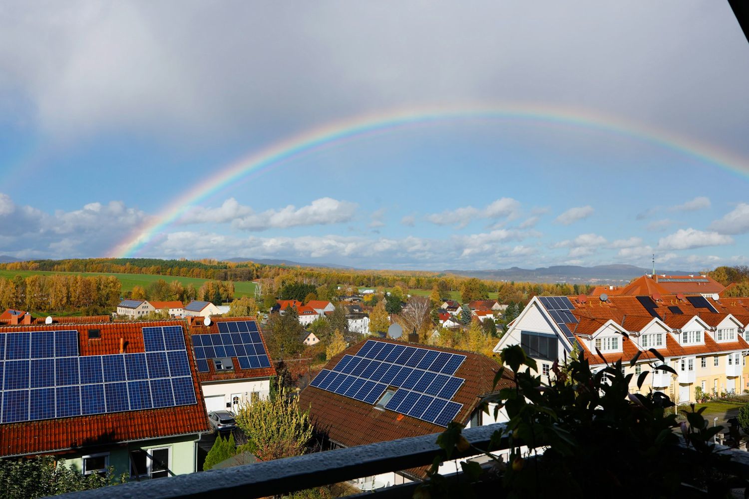 Rooftop solar panels on houses under a rainbow