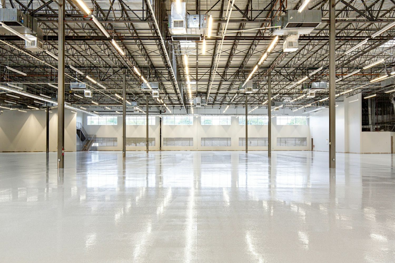 An empty warehouse with steel roof trusses and a polished floor